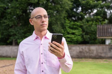 40 'lı yaşlarda kel, olgun bir erkek pembe gömlek ve gözlük takıyor. Kamp alanı çevresi ve karavan geçmişi var. Açık hava eğlence ortamında seyahat, turizm ve yaşam tarzı kavramı.