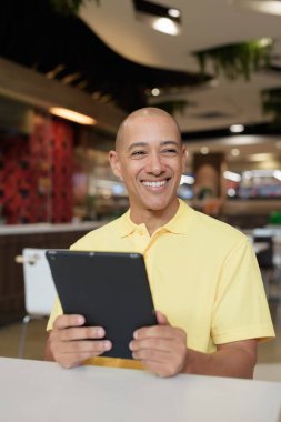 Modern bir lokantada dijital tablet bilgisayarla çalışan kel bir İtalyan 'ın portresi.