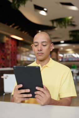 Modern bir lokantada dijital tablet bilgisayarla çalışan kel bir İtalyan 'ın portresi.