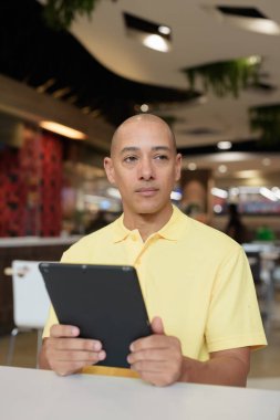 Modern bir lokantada dijital tablet bilgisayarla çalışan kel bir İtalyan 'ın portresi.