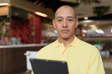 Modern bir lokantada dijital tablet bilgisayarla çalışan kel bir İtalyan 'ın portresi.