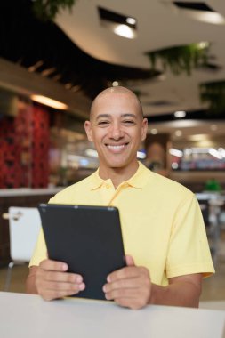 Modern bir lokantada dijital tablet bilgisayarla çalışan kel bir İtalyan 'ın portresi.