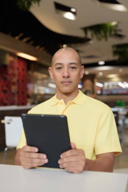 Modern bir lokantada dijital tablet bilgisayarla çalışan kel bir İtalyan 'ın portresi.