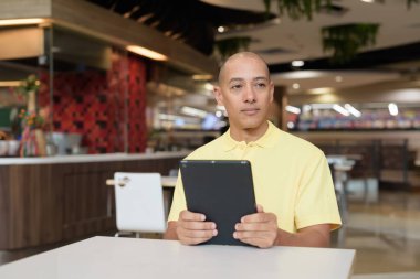 Modern bir lokantada dijital tablet bilgisayarla çalışan kel bir İtalyan 'ın portresi.