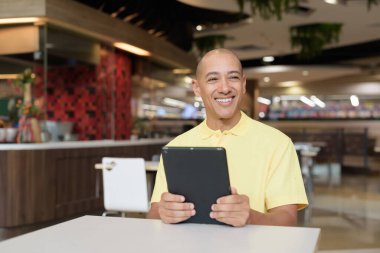 Modern bir lokantada dijital tablet bilgisayarla çalışan kel bir İtalyan 'ın portresi.