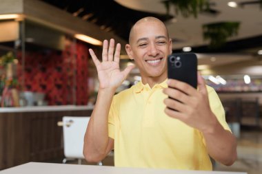 Yetişkin, kel bir İtalyan 'ın portresi modern bir lokantada oturmuş uzaktan kumandayla telefon kullanıyor.