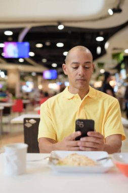 Yetişkin, kel bir İtalyan 'ın portresi modern bir lokantada oturmuş sağlıklı Hainanese tavuğu pilavı yiyor..