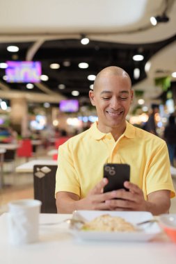 Yetişkin, kel bir İtalyan 'ın portresi modern bir lokantada oturmuş sağlıklı Hainanese tavuğu pilavı yiyor..