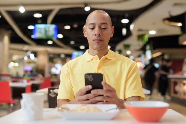 Yetişkin, kel bir İtalyan 'ın portresi modern bir lokantada oturmuş sağlıklı Hainanese tavuğu pilavı yiyor..