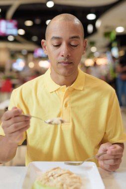 Yetişkin, kel bir İtalyan 'ın portresi modern bir lokantada oturmuş sağlıklı Hainanese tavuğu pilavı yiyor..