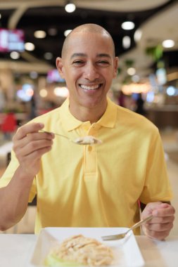 Yetişkin, kel bir İtalyan 'ın portresi modern bir lokantada oturmuş sağlıklı Hainanese tavuğu pilavı yiyor..