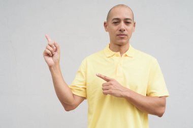 Saçları kazınmış, sarı polo tişörtlü yakışıklı bir İtalyan 'ın stüdyo portresi. Tarafsız beyaz bir duvarın önünde fotokopi alanı ile duruyor. Temiz, izole kesilmiş görünüm.