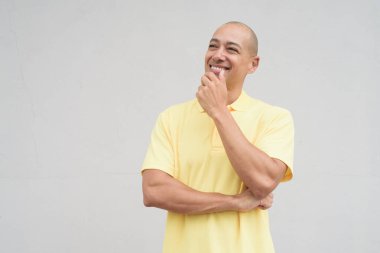 Saçları kazınmış, sarı polo tişörtlü yakışıklı bir İtalyan 'ın stüdyo portresi. Tarafsız beyaz bir duvarın önünde fotokopi alanı ile duruyor. Temiz, izole kesilmiş görünüm.