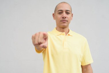 Saçları kazınmış, sarı polo tişörtlü yakışıklı bir İtalyan 'ın stüdyo portresi. Tarafsız beyaz bir duvarın önünde fotokopi alanı ile duruyor. Temiz, izole kesilmiş görünüm.