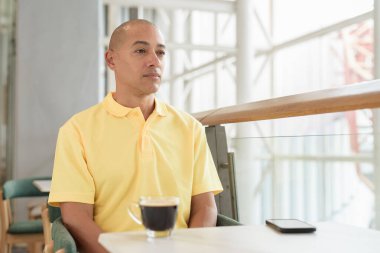 Gündüzleri kahve molası verirken şık bir kafede oturan kendinden emin, kel bir İtalyan. Modern yaşam tarzı ve iş konsepti.