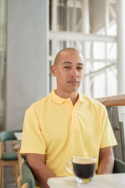 Gündüzleri kahve molası verirken şık bir kafede oturan kendinden emin, kel bir İtalyan. Modern yaşam tarzı ve iş konsepti.