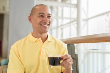 Gündüzleri kahve molası verirken şık bir kafede oturan kendinden emin, kel bir İtalyan. Modern yaşam tarzı ve iş konsepti.