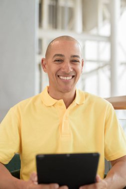 Gündüzleri dijital tablet bilgisayar kullanarak kahve molası verirken şık bir kafede oturan kendinden emin, kel bir İtalyan. Modern yaşam tarzı ve iş konsepti.