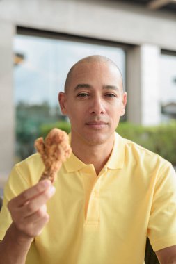 Orta yaşlı İspanyol bir adamın portresi açık havada oturmuş, öğle yemeği sırasında kızarmış tavuk yiyor, açık hava restoranlarında rahat bir hayat sürüyor..