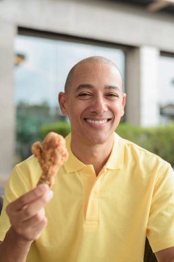 Orta yaşlı İspanyol bir adamın portresi açık havada oturmuş, öğle yemeği sırasında kızarmış tavuk yiyor, açık hava restoranlarında rahat bir hayat sürüyor..