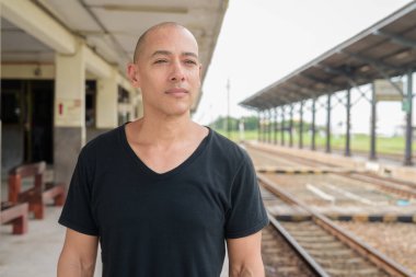 Tayland 'da seyahat ederken tren istasyonunda bekleyen siyah tişörtlü, olgun, kel bir İspanyol turistin portresi. Turizm, seyahat ve ulaşım teması.