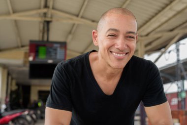 Tayland 'da seyahat ederken tren istasyonunda oturan siyah tişörtlü, olgun, kel bir İspanyol turistin portresi. Turizm, seyahat ve ulaşım teması.