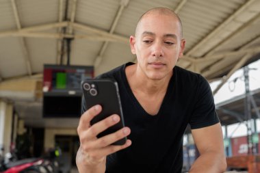 Tayland 'da seyahat ederken tren istasyonunda oturan siyah tişörtlü, olgun, kel bir İspanyol turistin portresi. Turizm, seyahat ve ulaşım teması.