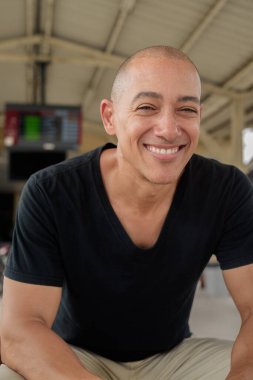 Tayland 'da seyahat ederken tren istasyonunda oturan siyah tişörtlü, olgun, kel bir İspanyol turistin portresi. Turizm, seyahat ve ulaşım teması.