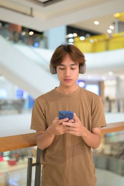 20 yaşında, müzik kulaklığı olan bir Taylandlı. AVM koridorunda telefon kullanıyor, mesajlaşıyor, online alışveriş yapıyor ve şehir hayatı sürüyor..