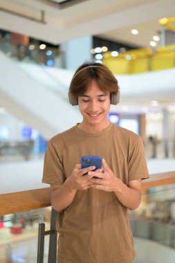 20 yaşında, kulaklıklı, müzik dinleyen Taylandlı. Parlak bir alışveriş merkezi koridorunda telefonuna gülümseyen, mesajlaşan, online alışveriş ve şehir hayatı tarzında bir adam..