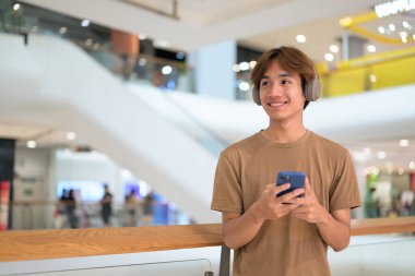 Boynuna kulaklık takmış 20 yaşındaki Taylandlı adam kafasında parlak bir alışveriş merkezi koridorunu, mesajlaşmayı, online alışverişi ve şehir yaşam tarzını araştırıyor..