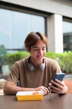 Kulaklıklı yakışıklı Asyalı genç Taylandlı modern yaşam tarzını seviyor.