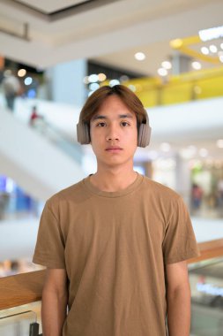 Kulaklıklı yakışıklı Asyalı genç Taylandlı müzik dinlerken modern yaşam tarzının tadını çıkarıyor.