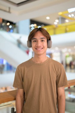 Kulaklıklı yakışıklı Asyalı genç Taylandlı modern yaşam tarzını seviyor.