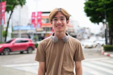 Kulaklıklı yakışıklı Asyalı genç Taylandlı yaz boyunca modern yaşam tarzının tadını çıkarıyor.