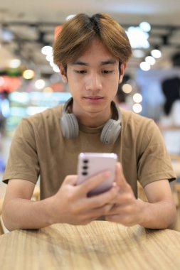 Kulaklıklı yakışıklı Asyalı genç Taylandlı modern yaşam tarzını seviyor.