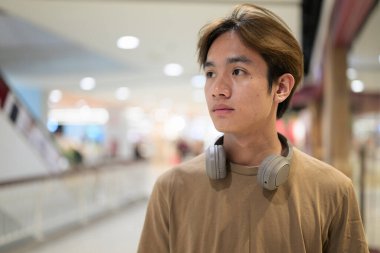 Kulaklıklı yakışıklı Asyalı genç Taylandlı modern yaşam tarzını seviyor.