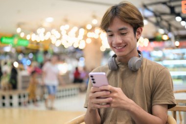 Kulaklıklı yakışıklı Asyalı genç Taylandlı modern yaşam tarzını seviyor.