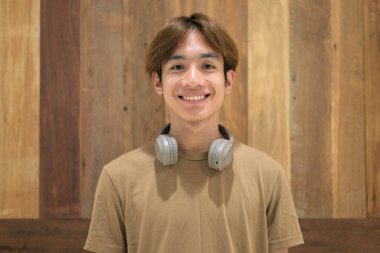 Kulaklıklı yakışıklı Asyalı genç Taylandlı modern yaşam tarzını seviyor.