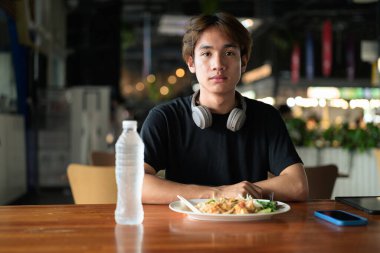 Tayland 'da Tayland erişteleri genç turistler tarafından yemek çubuklarıyla yenir. Asya 'da turistler ve yerliler tarafından sevilen ünlü sokak yemekleri..