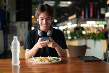 Tayland 'da Tayland erişteleri genç turistler tarafından yemek çubuklarıyla yenir. Asya 'da turistler ve yerliler tarafından sevilen ünlü sokak yemekleri..