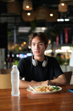 Tayland 'da Tayland erişteleri genç turistler tarafından yemek çubuklarıyla yenir. Asya 'da turistler ve yerliler tarafından sevilen ünlü sokak yemekleri..