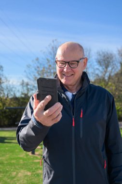 Senior man in sportswear using mobile phone while exercising in the park during day