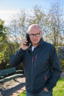Senior man in sportswear using mobile phone while exercising in the park