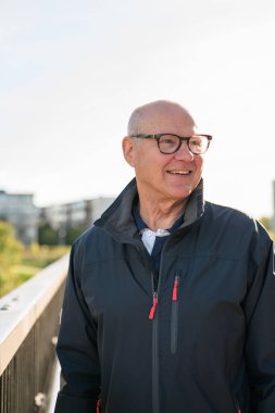 Portrait of a smiling Scandinavian senior man standing on a bridge in the city