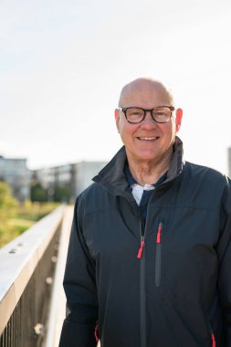 Portrait of a smiling Scandinavian senior man standing on a bridge in the city