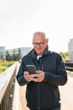 Happy senior man using mobile phone in the city. Technology concept.