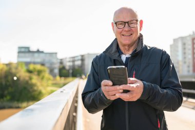 Happy senior man using mobile phone in the city. Technology concept.