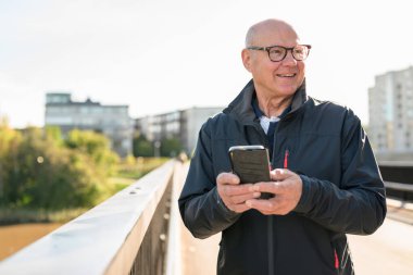 Happy senior man using mobile phone in the city. Technology concept.
