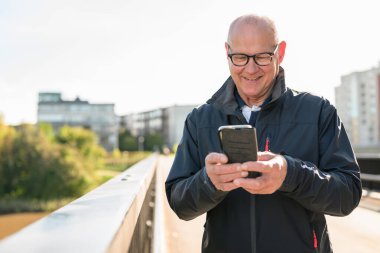 Happy senior man using mobile phone in the city. Technology concept.